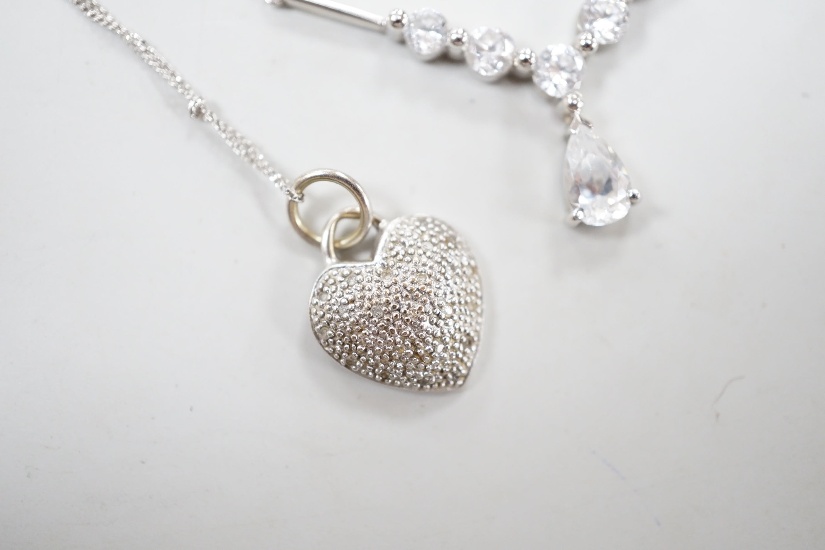 Two modern white metal (stamped 375) and gem set pendant necklaces, including a diamond chip set heart, longest 50cm